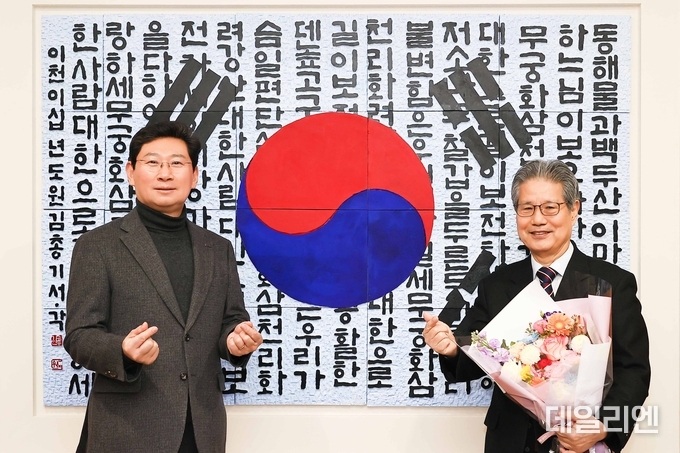 태극기와 애국가 가사를 담은 서각 작품을 용인특례시에 기증한 김총기 작가(오른쪽)가 이상일 시장과 24일 열린 작품 제막식에서 기념촬영을 하고 있다..