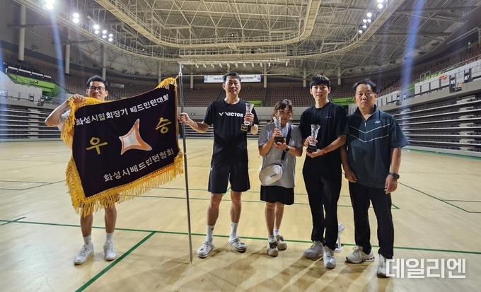 제6회 화성특례시의회 의장기 배드민턴대회에서 우승을 차지한 에이스클럽과 준우승 장안클럽, 3위 닥공클럽 정영모 협회장 등이 우승기와 트로피를 들고 기념촬영을 하고 있다.