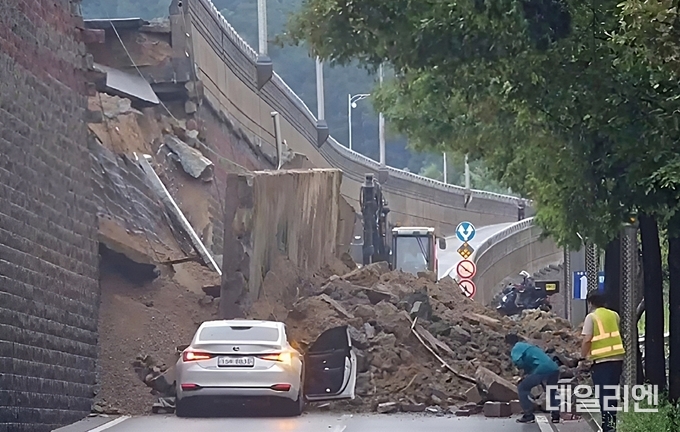 지난 16일 오후 오산시 가장동 고가도로 아래 옹벽이 붕괴돼 차량이 매몰되고 흙더미가 도로를 뒤덮은 현장. 이 사고로 차량 2대가 토사에 휩쓸려 1명이 숨지고 1명이 자력 탈출했다. 소방당국과 구조 인력이 현장 복구 작업을 벌이고 있다.