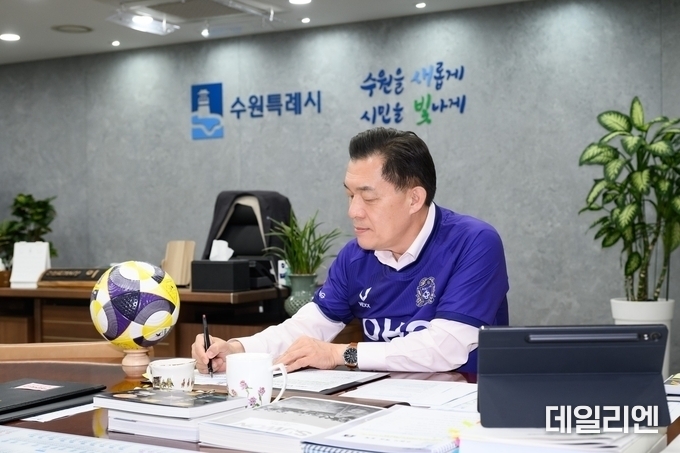 이재준 수원특례시장이 ‘지지대 더비’ 패장 공약 이행 위해 FC안양 유니폼을 입고 집무를 보고 있다. 이 시장은 지난 4월 25일 자신의 SNS에 사진을 게시하며 “약속은 지키라고 있는 것”이라며 유쾌한 승부의 의미를 강조했다.