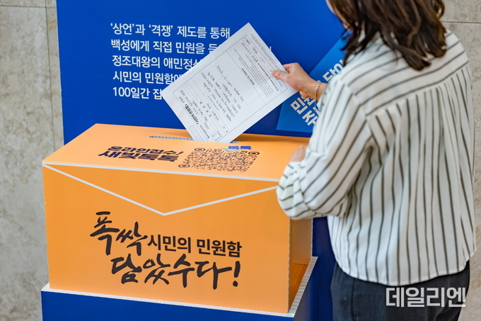 한 시민이 ‘폭싹 담았수다! 시민의 민원함 신청서’를 작성한 뒤 수원시청에 설치된 민원함에 넣고 있다.