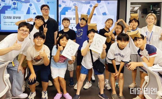 디지털 공부방에 참여한 대학생 멘토와 초등학생 멘티가 광명시디지털혁신교육센터에서 AI가 그린 초상화를 들고 기념사진을 촬영하고 있다