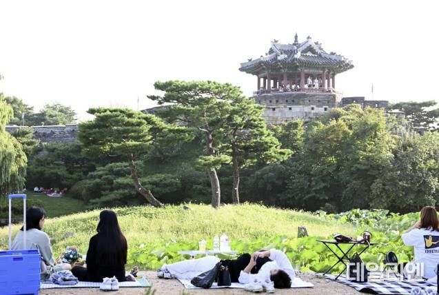 시민들이 수원화성 방화수류정이 보이는 용연에서 가을 피크닉을 즐기고 있다.