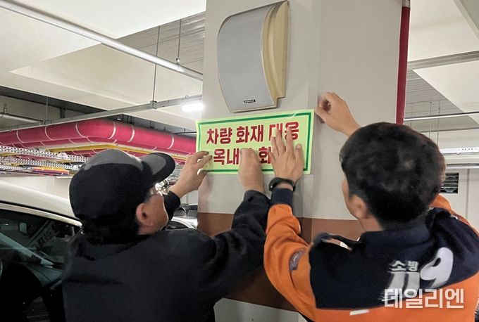 지하주차장에 옥내소화전 스티커를 부착하고 있는 모습